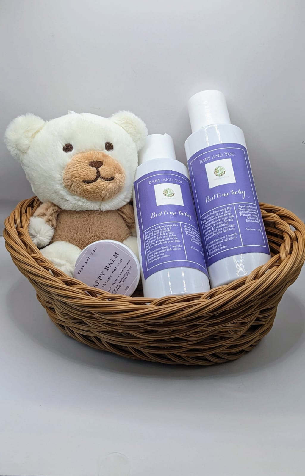 New born gift basket contains 100ml bedtime baby hair and body wash, 100ml bedtime baby massage oil, 30g natural nappy balm and small teddy.